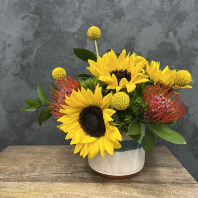 Sunflowers and greenery in a small vase.