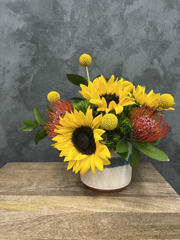 Sunflowers and greenery in a small vase.