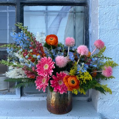 Colorful custom flower arrangement sitting on a window ledge.