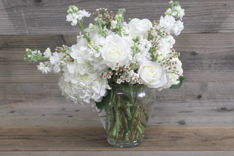 Tulips, carnations and seasonal foliage, all tied together and presented in a glass vase.