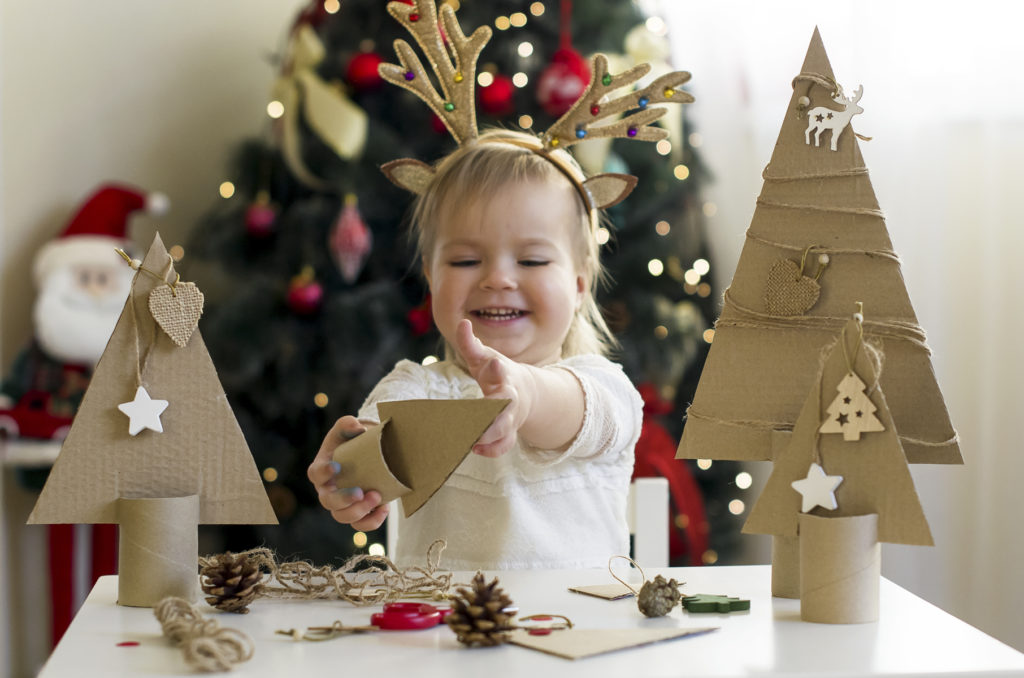 Funny child girl making decorations for christmas Handmade Christmas trees from natural materials. 