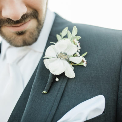 White boutonniére pinned on a black wedding suit.