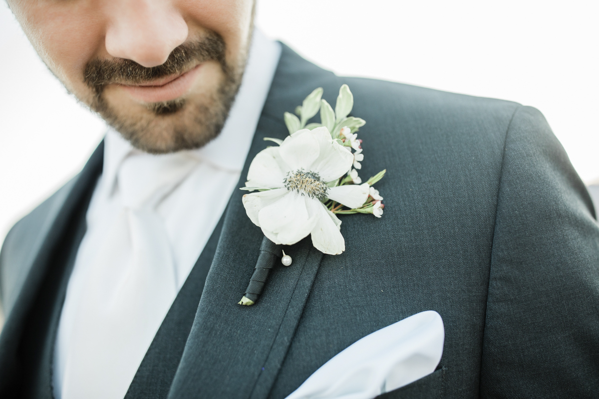 White boutonniére pinned on a black wedding suit.