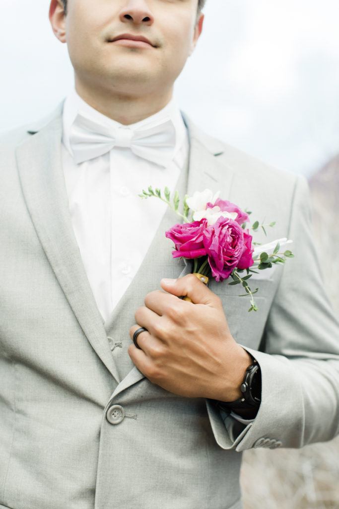 Groom with a pink wedding boutonniere on a gray suit.