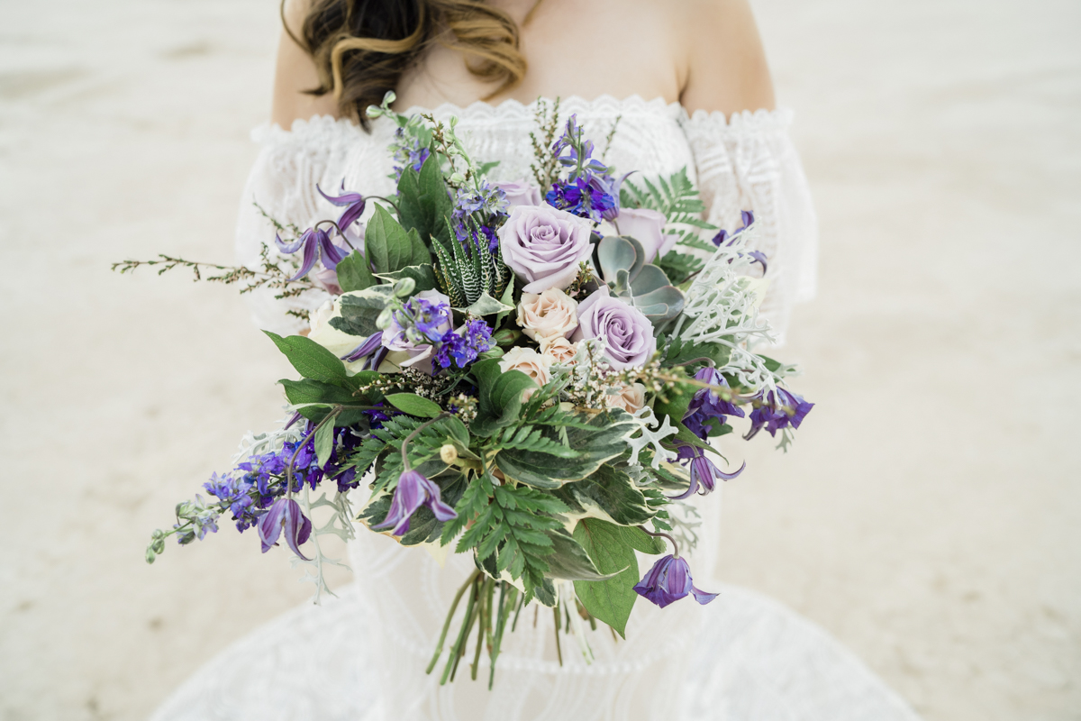 Wedding bouquet of greenery and purple flowers.