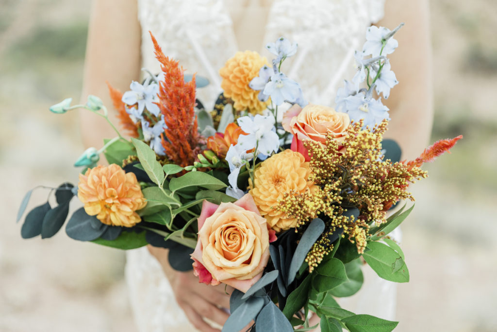 Bride holding a wedding bouquet of orange and white flowers.