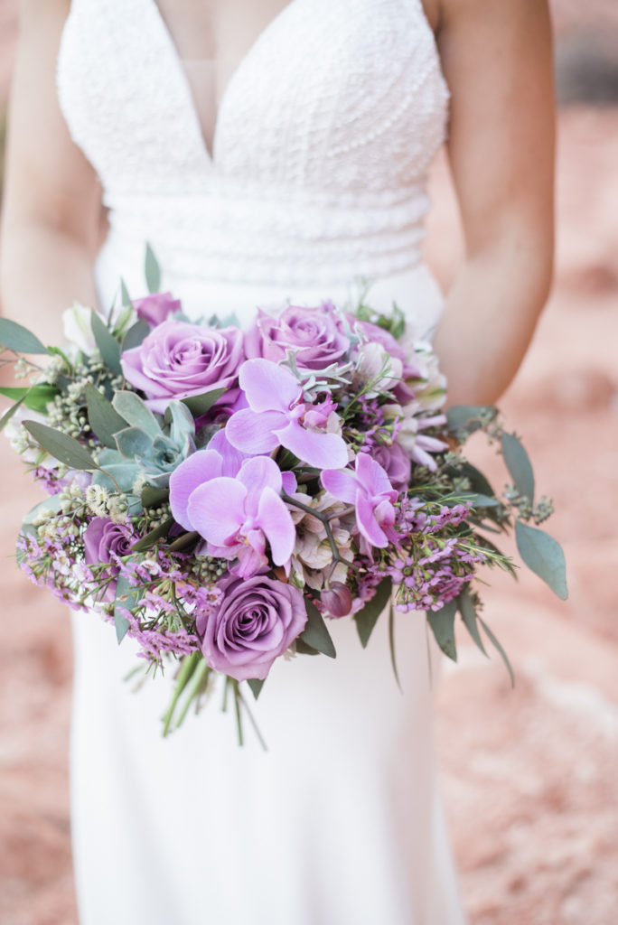 Bride holding a wedding bouquet of purple flowers and green succulents.