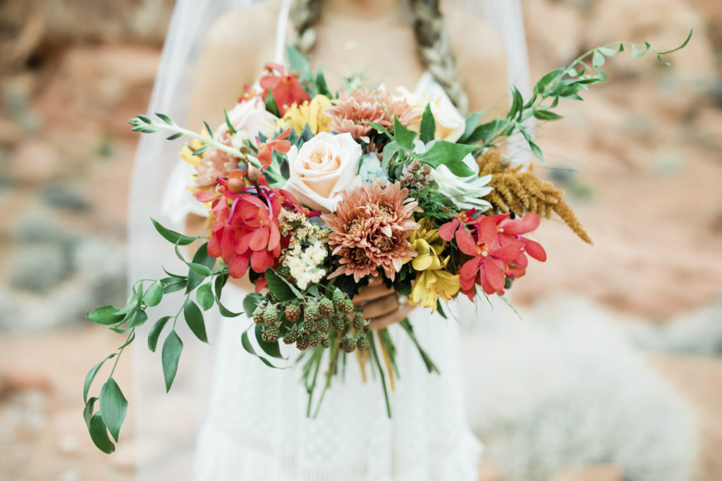 Bride holding garden wedding bouquet of fall colored flowers.