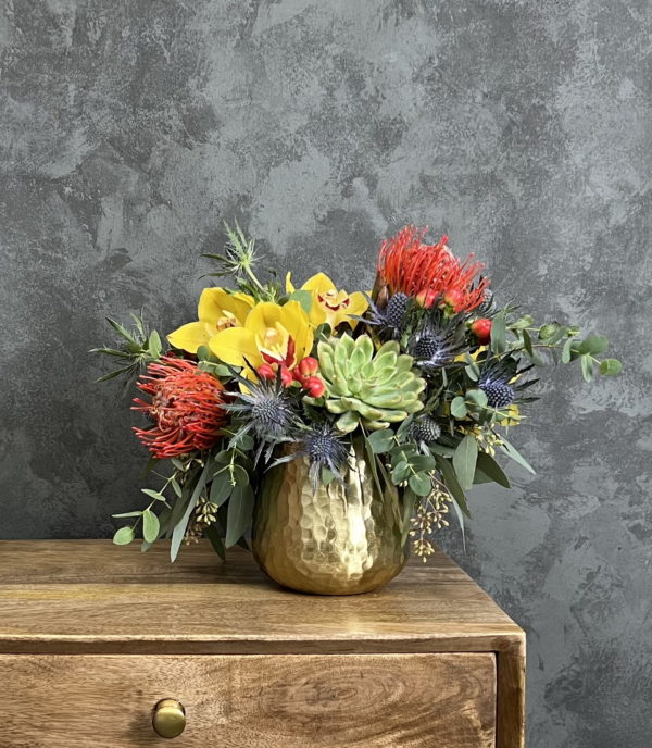 Colorful flower and succulent arrangement in brass vase.