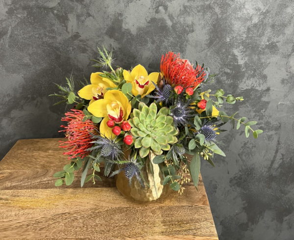 Colorful flower and succulent arrangement in brass vase.