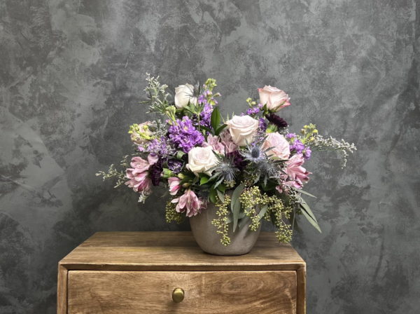 Light purple flower arrangement in a clay vase.