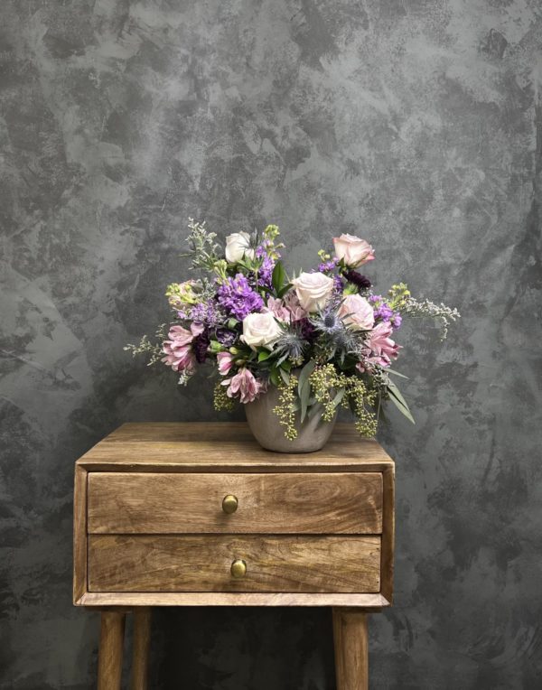 Light purple flower arrangement in a clay vase.