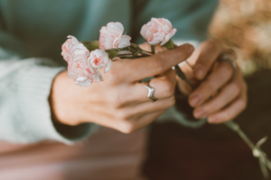 Hands hold four small flower stems.