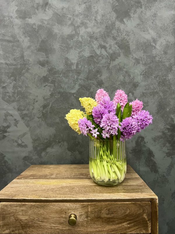 Glass vase holding pink and yellow hyacinth flowers.