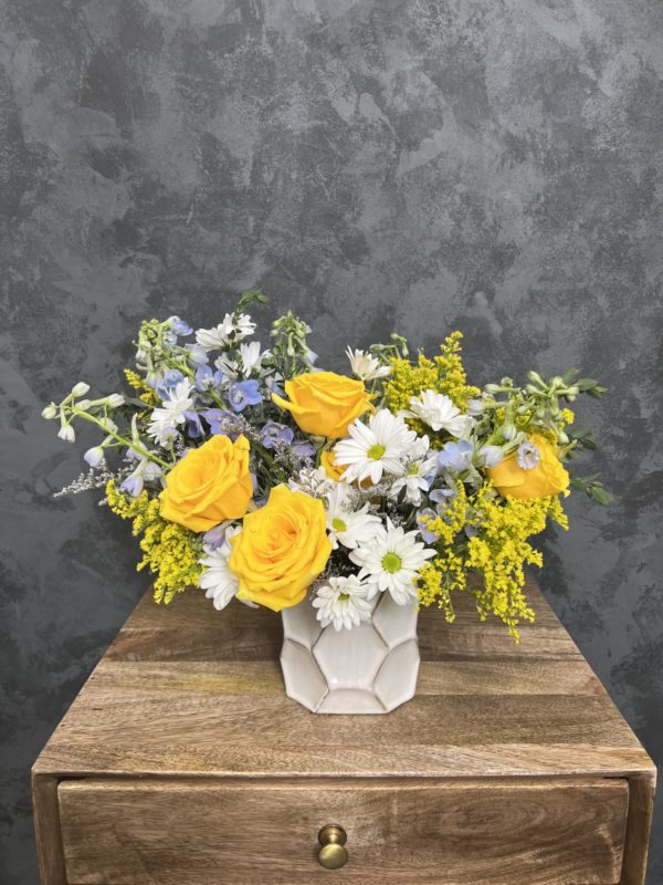 Mother's day flower arrangement of yellow and white flowers in a honeycomb shaped vase.