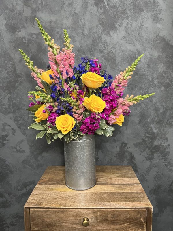 Color flower arrangement in a tall metal vase.