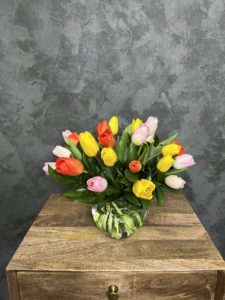 Clear glass vase of colorful tulips.