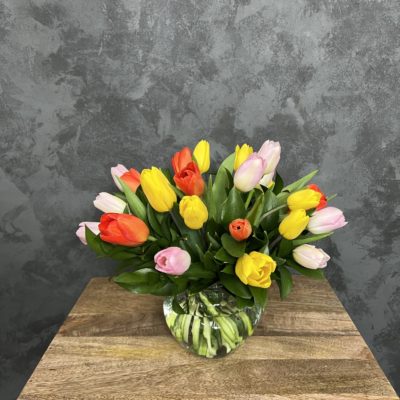 Clear glass vase of colorful tulips.