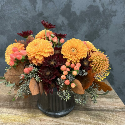 Autumn themed flower arrangement in gray vase.