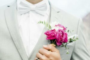 Groom with pink boutonnière on a gray suit.