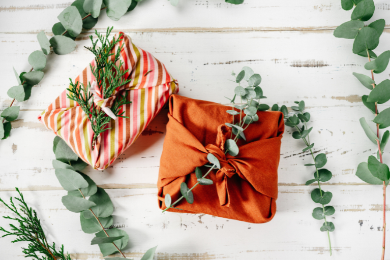Christmas gifts wrapped with fabric and greenery.