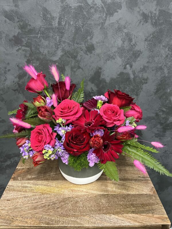Valentine's flower arrangement of pinks and red in a white ceramic vase.