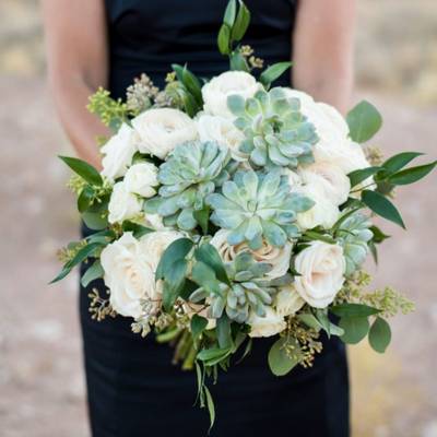 Large flower and succulent bridesmaid's bouquet held in hands.