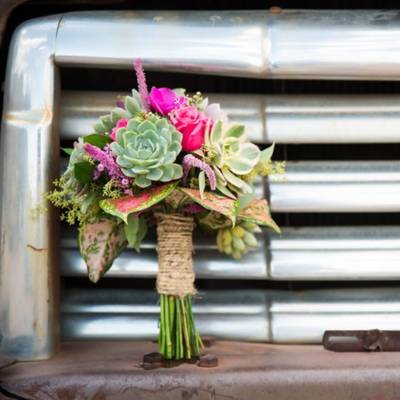 Rustic wrapped bridesmaid's bouquet sitting on a truck fender.