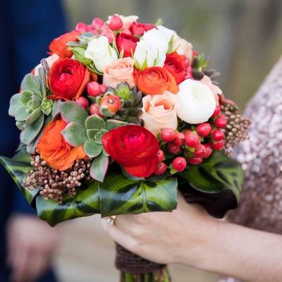 Small bridesmaid's bouquet of red, orange and white flowers and greenery.