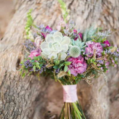 Bridesmaids flowers in a small bouquet resting against a tree.