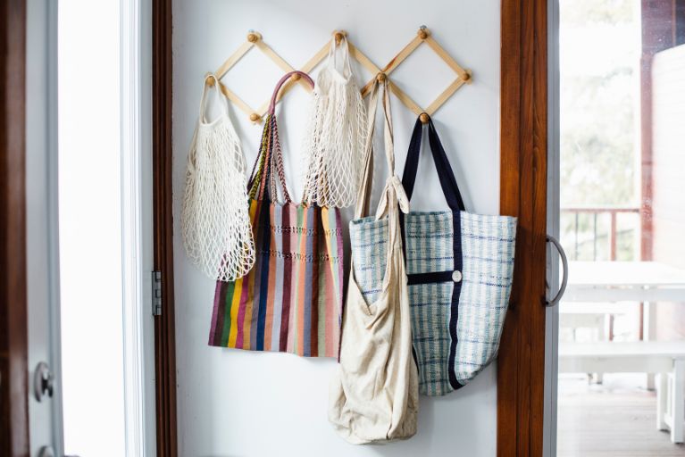 Reusable shopping bags hanging from hooks.
