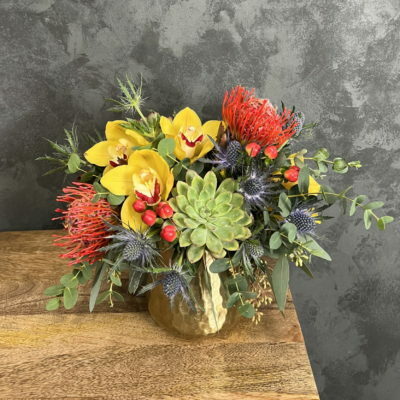 Mix of flowers and succulents in a brass vase.