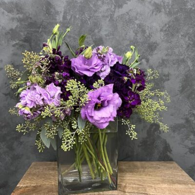Colorful bouquet of purple flowers in a clear vase.