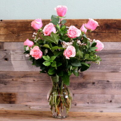 Dozen pink roses in a clear, glass vase.
