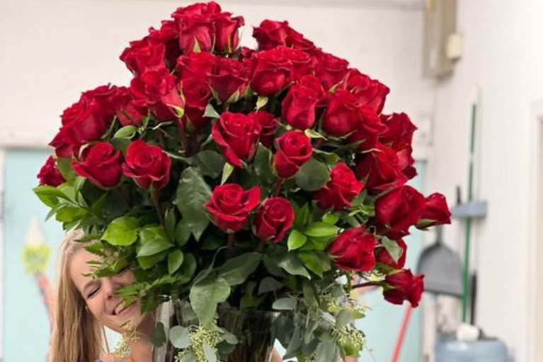 Woman holding a large bunch of red roses.