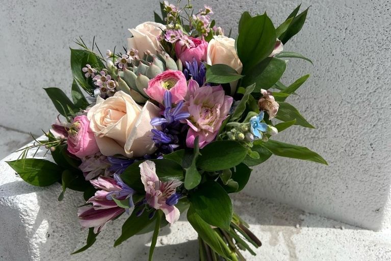 Wedding bouquet made of pink and purple flowers and greenery.