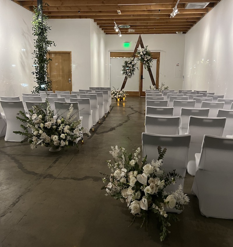 Event space with chairs in two rows and flowers at the front and sides of the room.