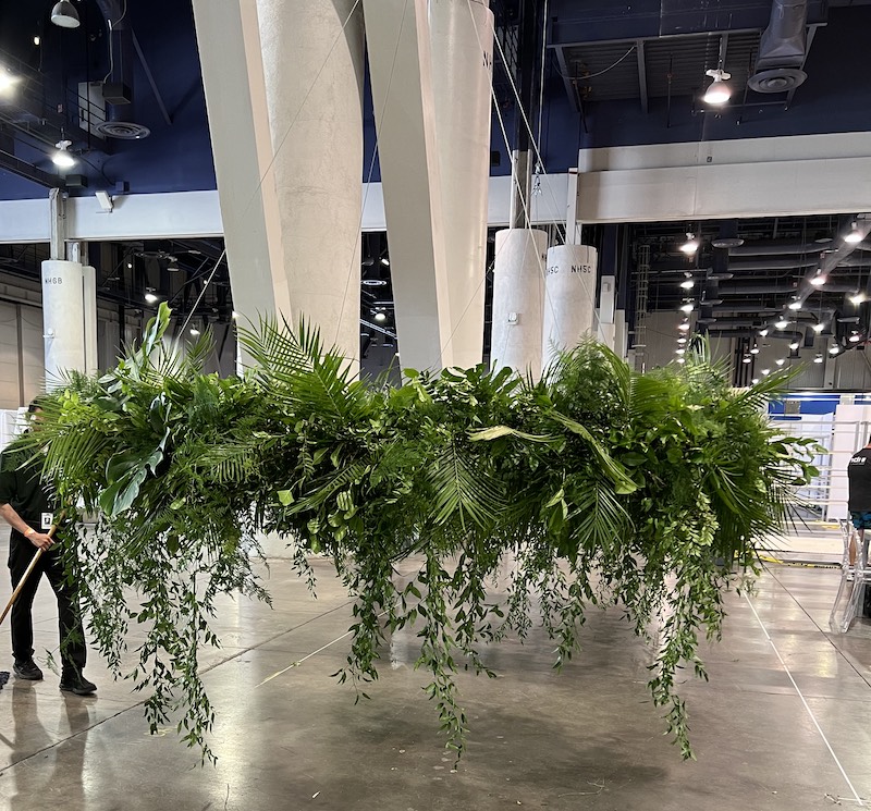 Large group of greenery hung from the ceiling at an event center.