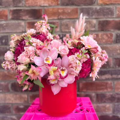 large flower arrangement in a red vase made of pink and read florals