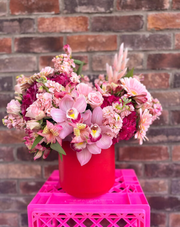 large flower arrangement in a red vase made of pink and read florals