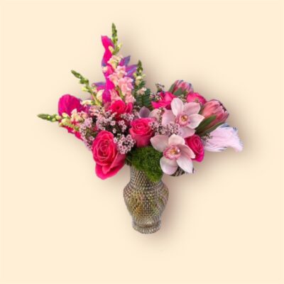 colorful flower arrangement of pink flowers and feathers in a shiny vase