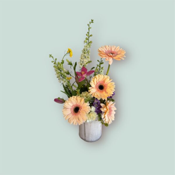 peach gerbera daisies and wildflowers in a ceramic vase