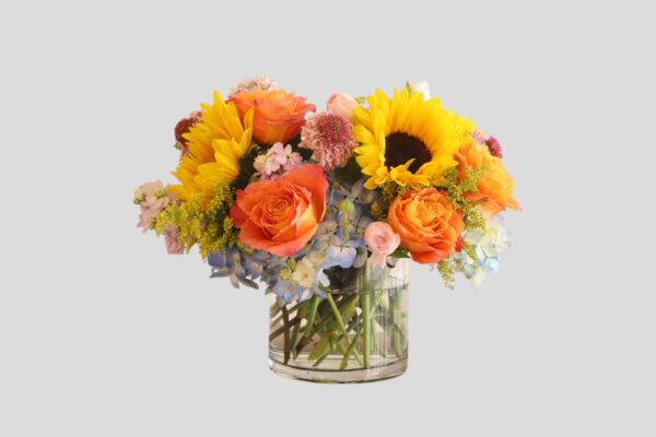 flower arrangement of hydrangea, sunflowers, roses and in a round glass vase