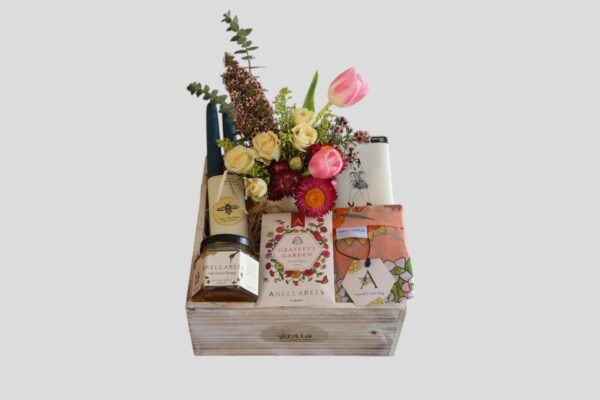white wooden mother's day gift crate filled with a flower bouquet, honey, chocolates, flowers seeds, and candles