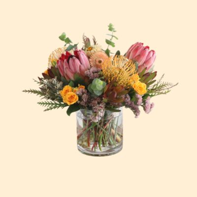 flower arrangement of proteas and yellow flowers in a glass vase