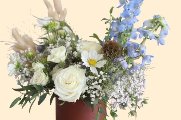 flower arrangement of white and blue flowers in a brown vase