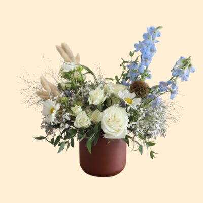 flower arrangement of white and blue flowers in a brown vase