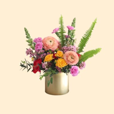 cheerful flower arrangement of pink and peach flowers in a gold vase