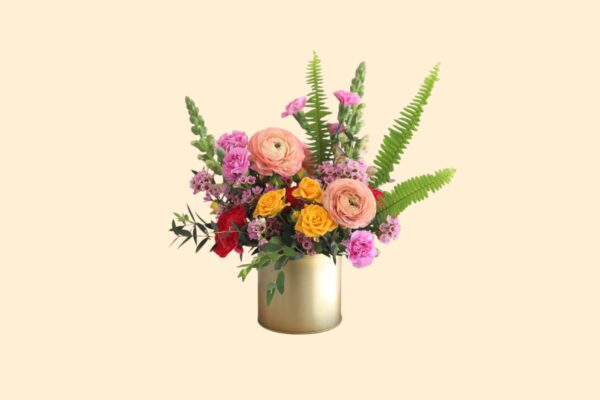 cheerful flower arrangement of pink and peach flowers in a gold vase